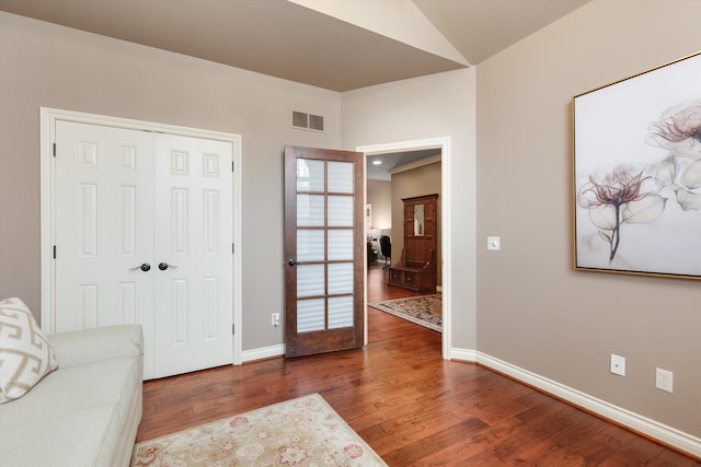 sitting room with vaulted ceiling, hardwood / wood-style flooring, visible vents, and baseboards