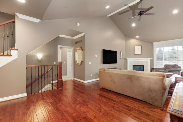 living area with recessed lighting, a glass covered fireplace, wood finished floors, high vaulted ceiling, and baseboards