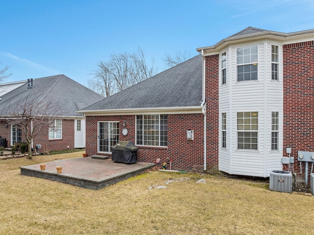 back of property featuring roof with shingles, cooling unit, a lawn, and a patio