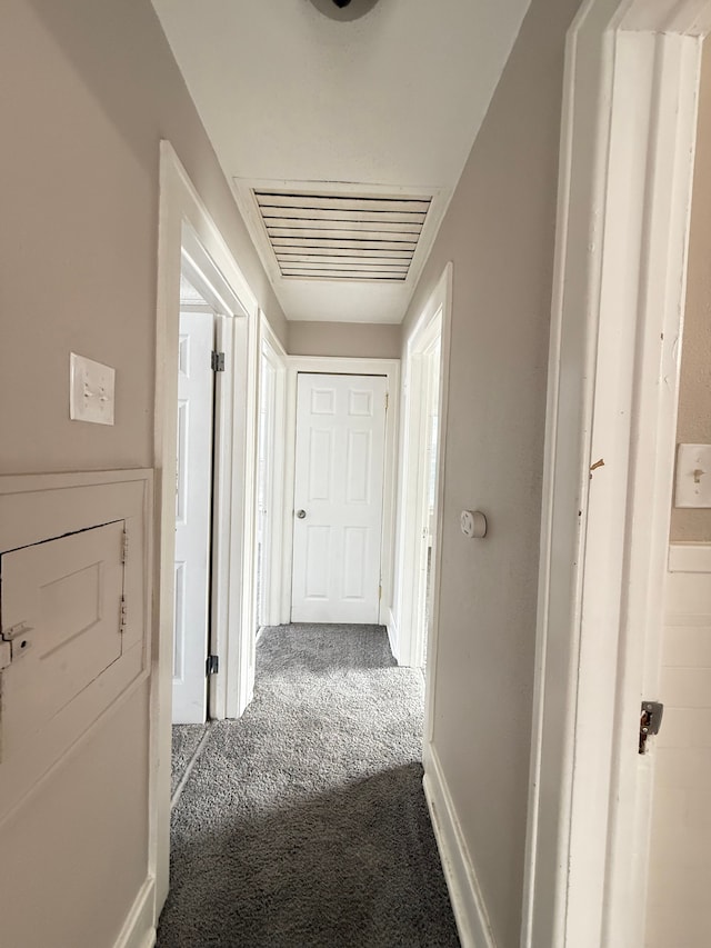 hallway featuring carpet flooring, visible vents, and baseboards