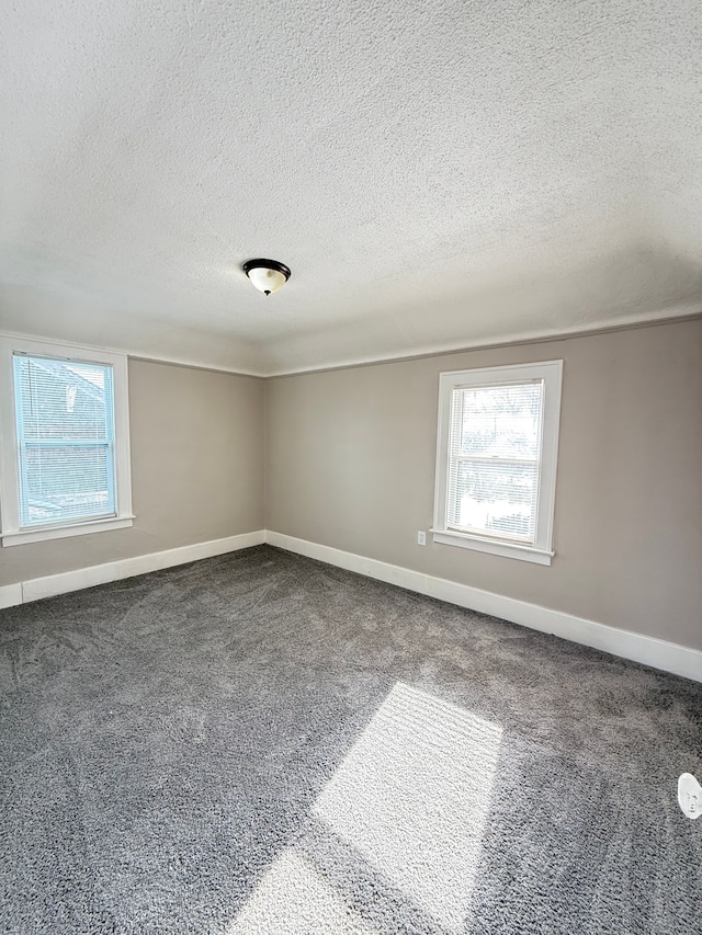 carpeted spare room with a textured ceiling and baseboards