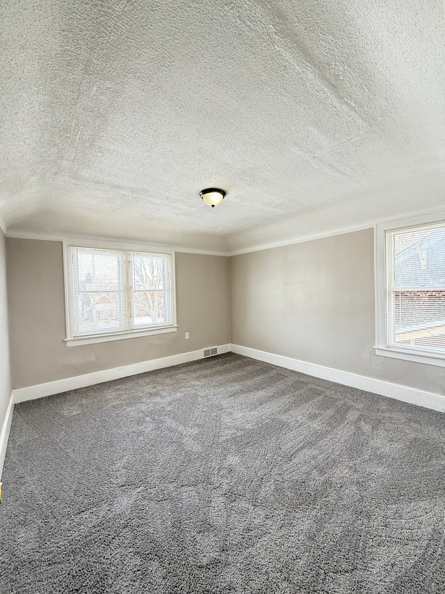 unfurnished room with carpet flooring, visible vents, baseboards, and a textured ceiling