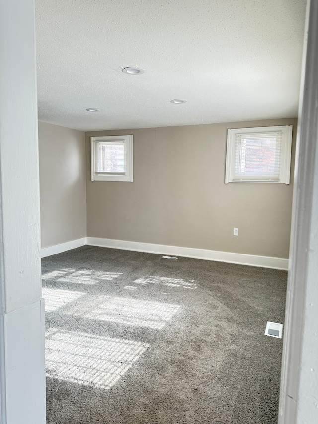 spare room featuring baseboards, a textured ceiling, visible vents, and carpet flooring