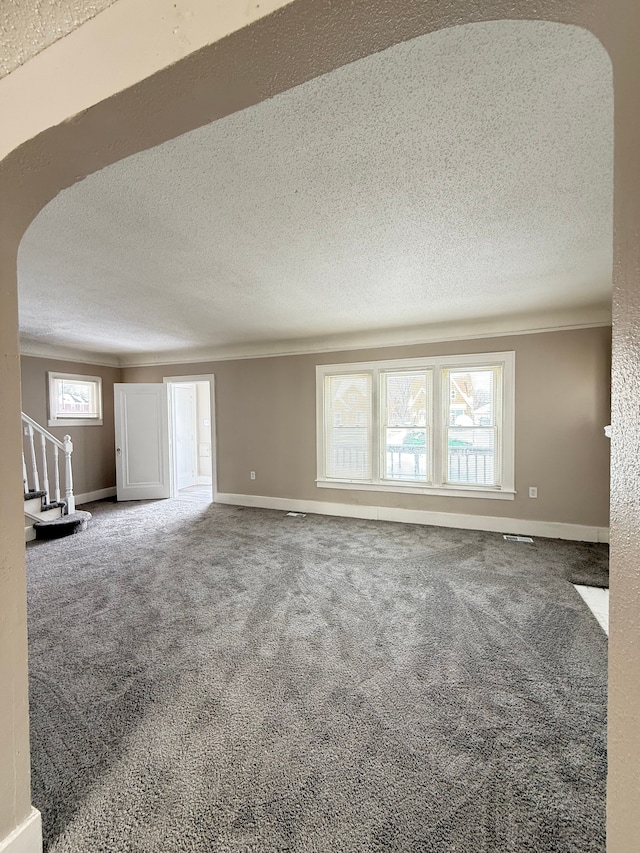 spare room with arched walkways, stairway, carpet, and a textured ceiling