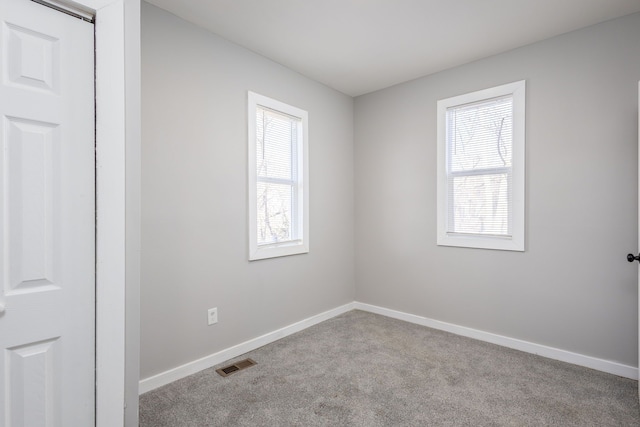 empty room featuring baseboards, visible vents, and carpet flooring