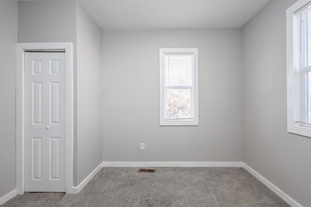 spare room featuring carpet floors, visible vents, and baseboards