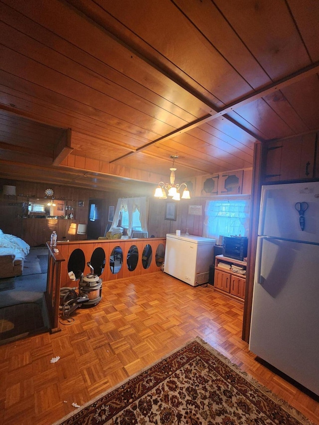 interior space featuring fridge, wooden walls, a chandelier, and freestanding refrigerator