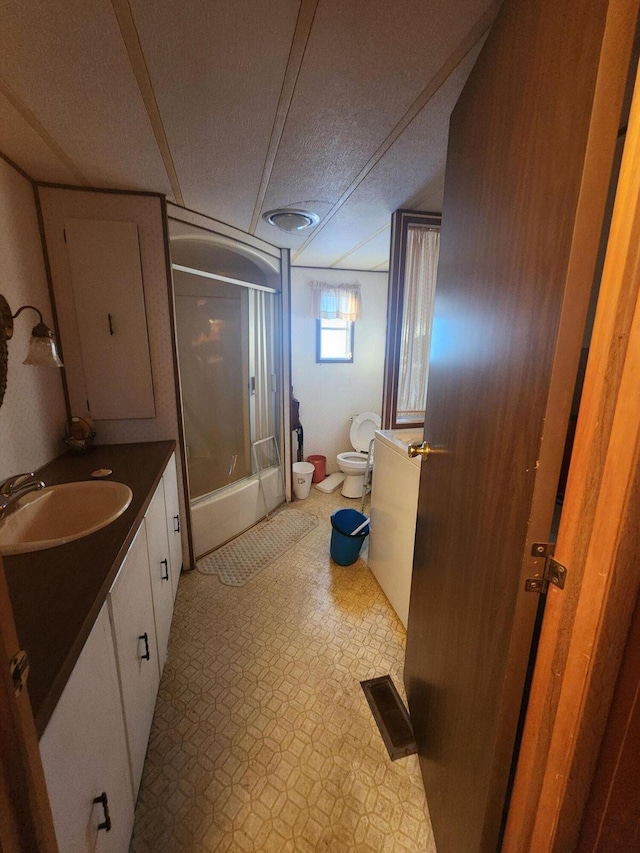 bathroom featuring visible vents, bath / shower combo with glass door, toilet, tile patterned floors, and vanity