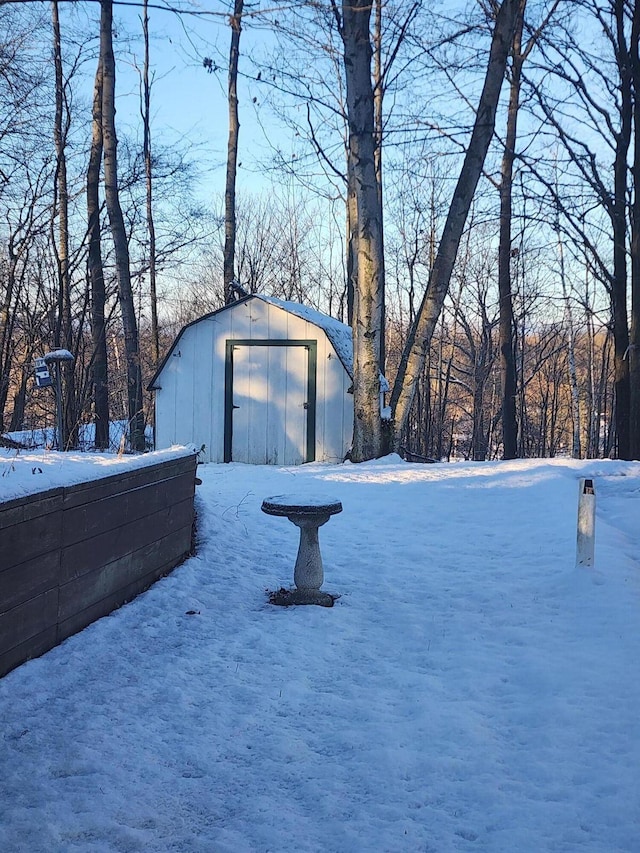 snow covered garage featuring a shed