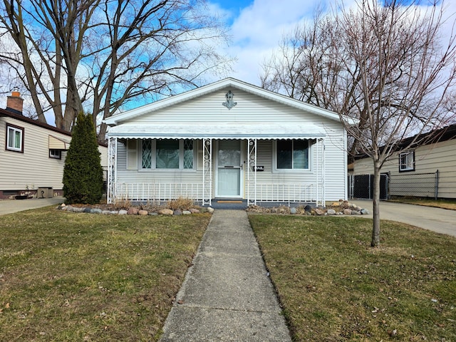 bungalow-style home with a front yard and fence