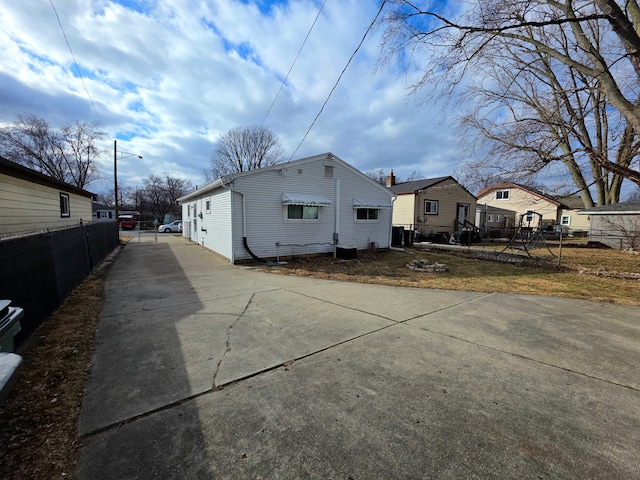 view of side of property with a residential view, central AC, and fence