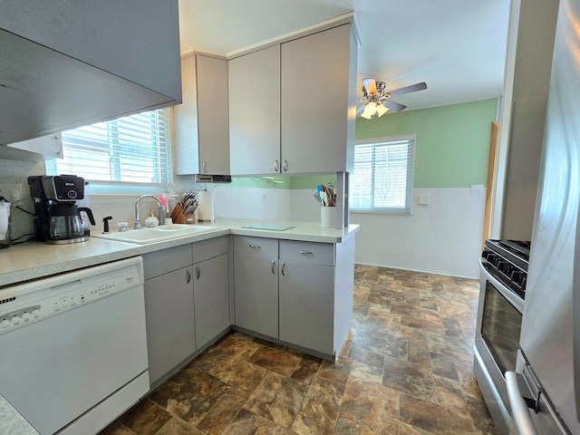 kitchen with appliances with stainless steel finishes, stone finish flooring, a healthy amount of sunlight, and a sink