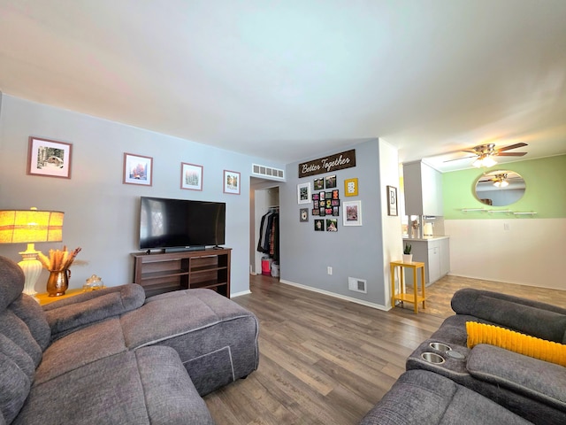 living room featuring a ceiling fan, baseboards, visible vents, and wood finished floors