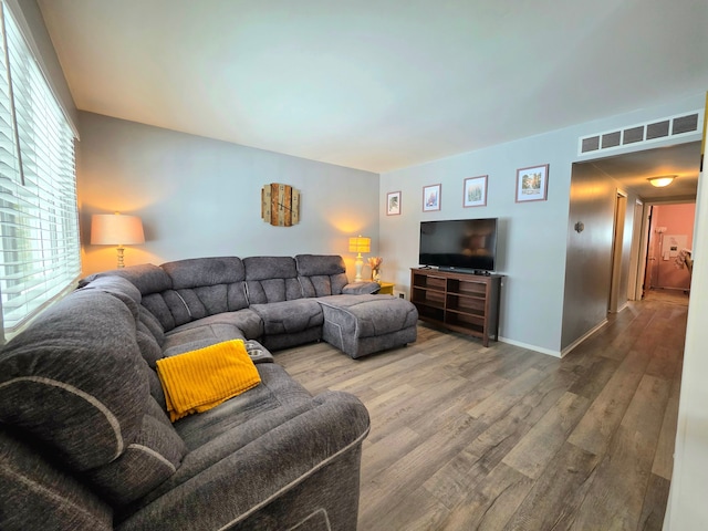 living area featuring wood finished floors, visible vents, and baseboards