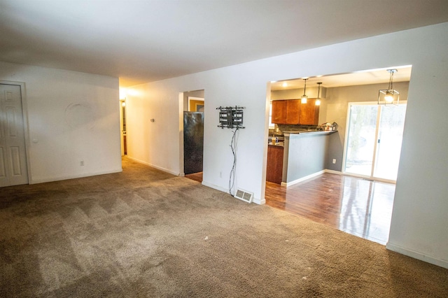 unfurnished living room featuring visible vents and carpet flooring