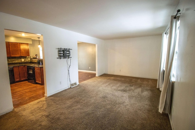 empty room featuring dark carpet and baseboards
