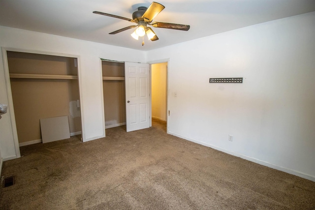 unfurnished bedroom featuring baseboards, visible vents, a ceiling fan, carpet, and two closets