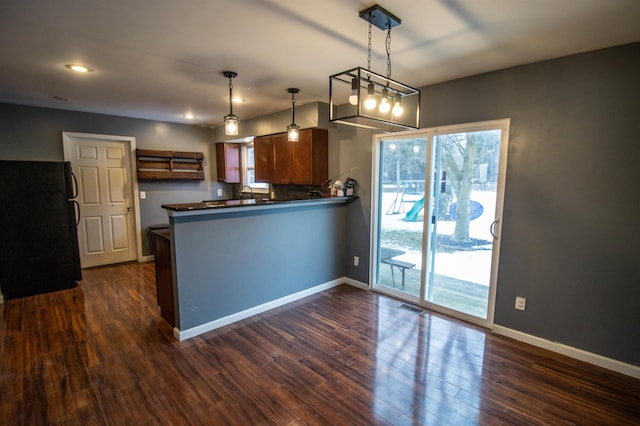 kitchen with freestanding refrigerator, dark wood-style flooring, a peninsula, dark countertops, and baseboards