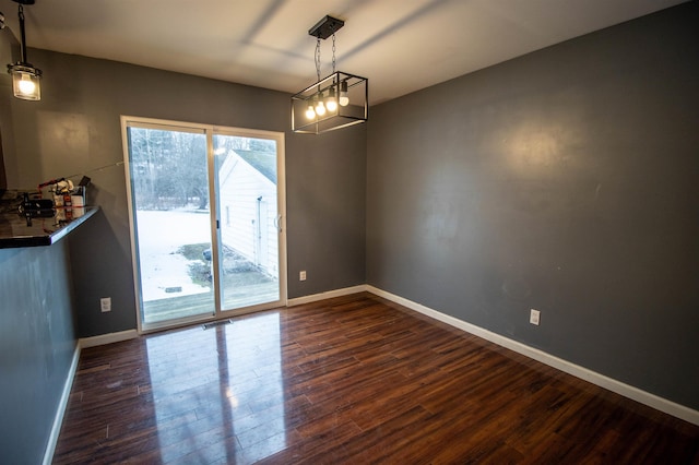 unfurnished dining area featuring dark wood-type flooring and baseboards
