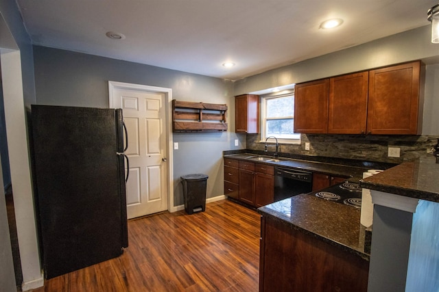 kitchen with black appliances, a sink, dark wood-style flooring, decorative backsplash, and baseboards