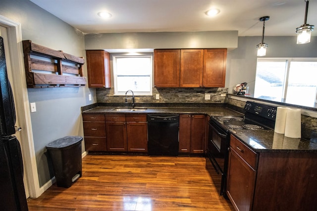 kitchen with a peninsula, a sink, decorative backsplash, dark wood-style floors, and black appliances