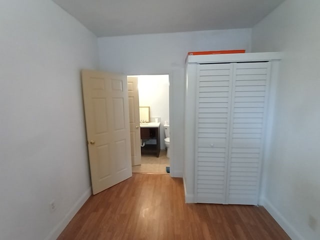 unfurnished bedroom with a closet, baseboards, and wood finished floors