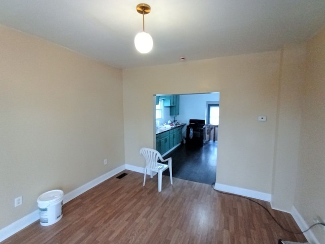 unfurnished room with dark wood-type flooring, visible vents, and baseboards