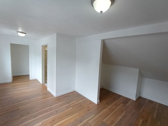 bonus room featuring light wood-type flooring, lofted ceiling, and baseboards