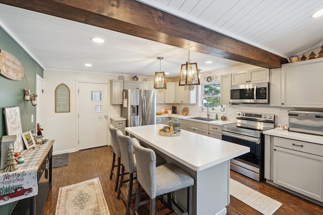 kitchen with beam ceiling, light countertops, appliances with stainless steel finishes, a sink, and a kitchen bar