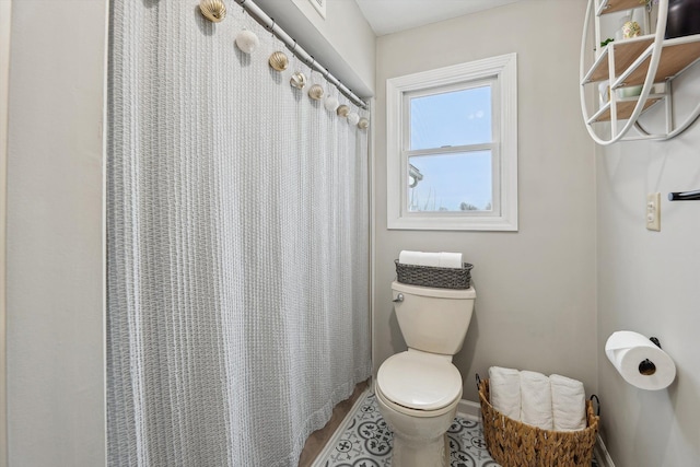 full bathroom featuring a shower with shower curtain, toilet, and baseboards