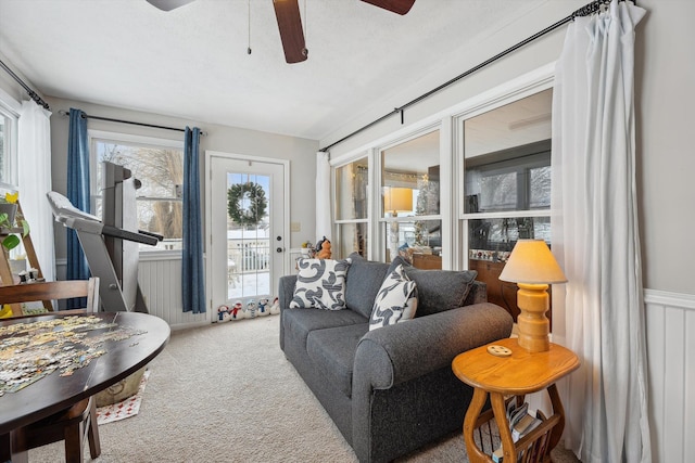 carpeted living area with a wainscoted wall, ceiling fan, and a textured ceiling