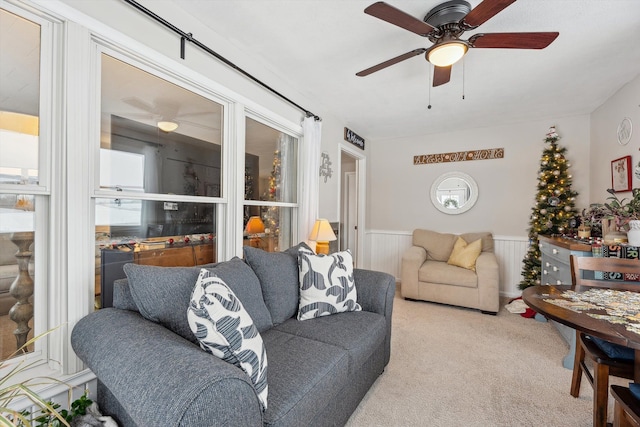 living room with carpet, wainscoting, a wealth of natural light, and a ceiling fan