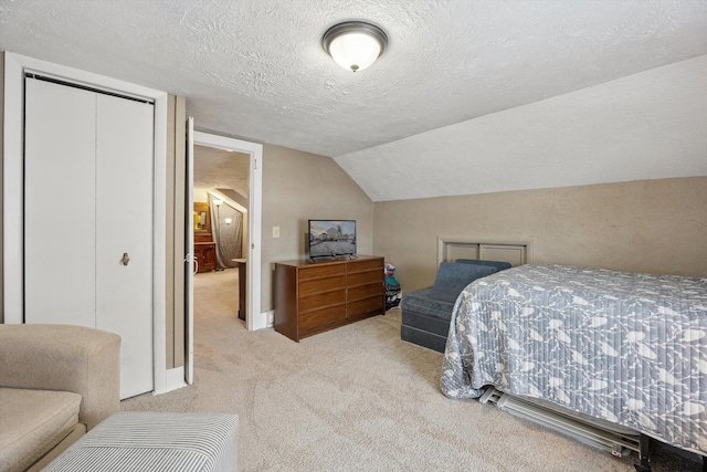 bedroom with a textured ceiling, a closet, carpet, and lofted ceiling