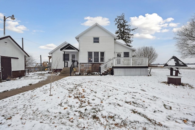 snow covered back of property with stone siding and a wooden deck