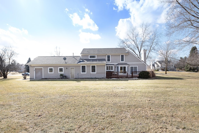 rear view of house featuring a garage, a chimney, a lawn, and a wooden deck