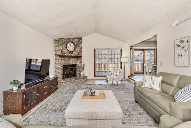 living area featuring a brick fireplace, vaulted ceiling, a textured ceiling, and wood finished floors