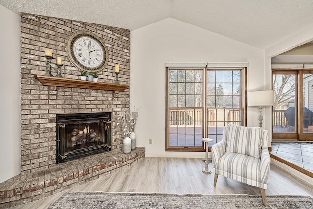 sitting room featuring lofted ceiling, a fireplace, a textured ceiling, and wood finished floors