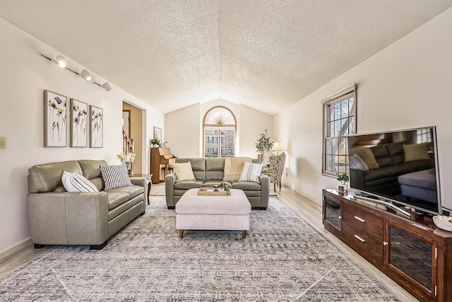 living area with a textured ceiling, baseboards, vaulted ceiling, and wood finished floors