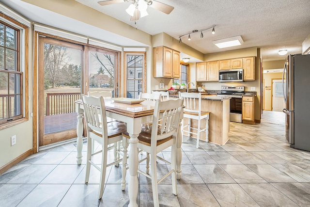 dining area featuring light tile patterned floors, baseboards, ceiling fan, rail lighting, and a textured ceiling