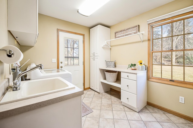 laundry room with cabinet space, plenty of natural light, light tile patterned floors, and a sink