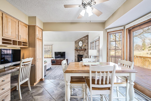 tiled dining area featuring ceiling fan, a textured ceiling, visible vents, a brick fireplace, and built in study area