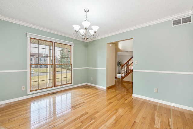 unfurnished room with ornamental molding, light wood-type flooring, visible vents, and a notable chandelier