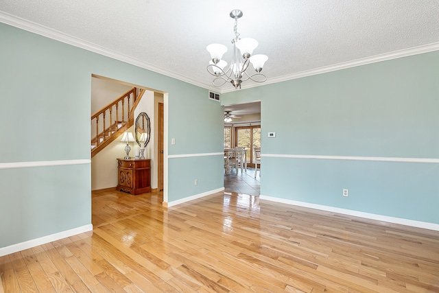 spare room featuring a textured ceiling, visible vents, baseboards, ornamental molding, and light wood finished floors