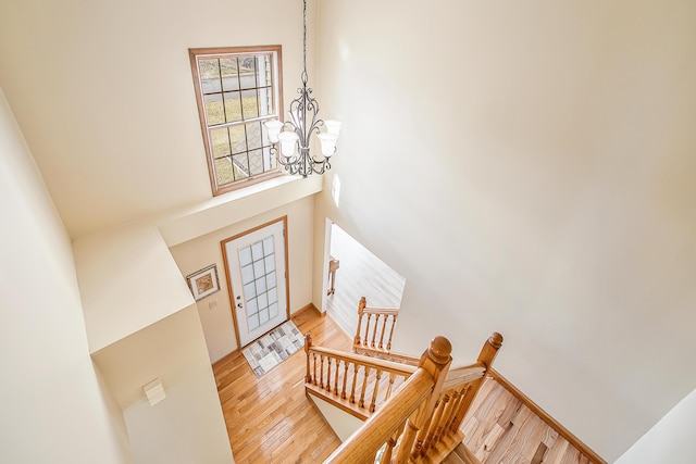 foyer entrance featuring light wood-type flooring, a towering ceiling, and a chandelier