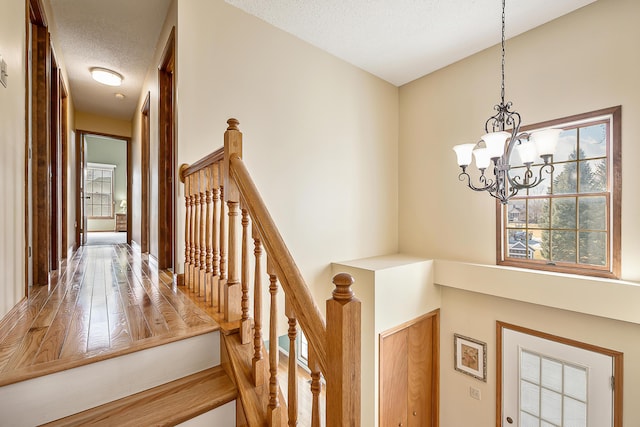 staircase featuring a notable chandelier and a textured ceiling