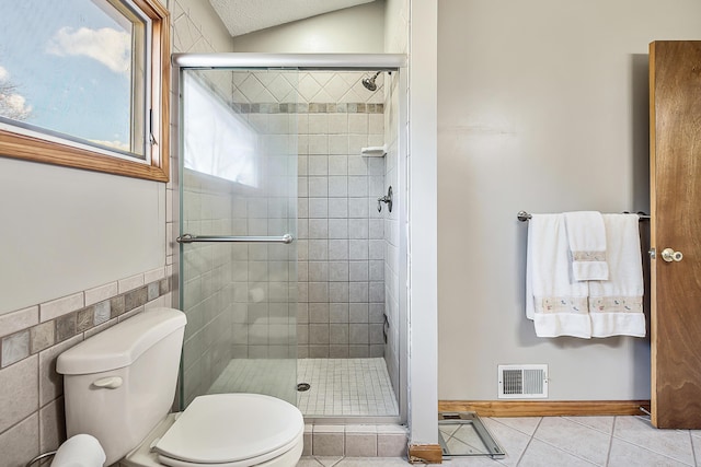 bathroom with tile walls, visible vents, toilet, a shower stall, and tile patterned floors