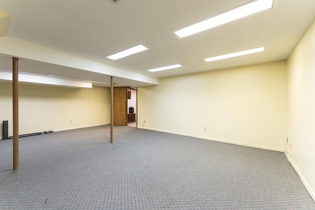 finished below grade area featuring dark colored carpet and baseboards