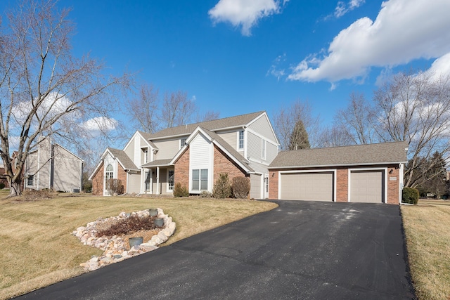 traditional home with an attached garage, driveway, a front lawn, and brick siding