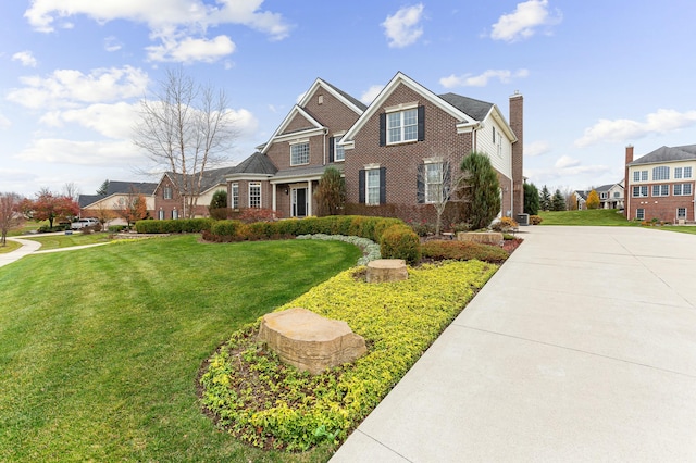 view of front of home with brick siding, a front lawn, and a chimney