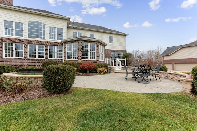 rear view of house featuring a yard, a patio, and brick siding